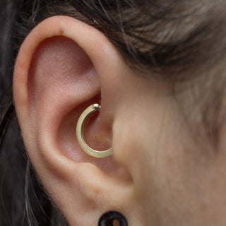 An ear with the Chen 14k gold clicker ring in a Daith piercing