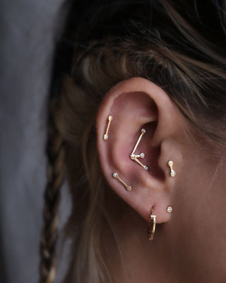 a styled ear with gold piercing jewelry, set with diamonds