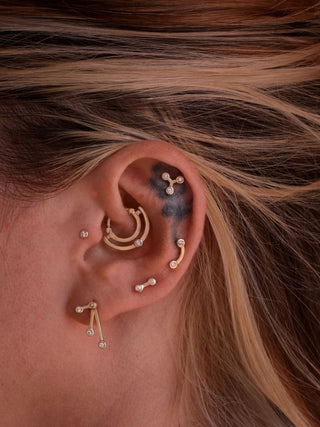 an ear with gold piercing jewelry