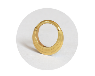 Introducing the New Era design: a piercing clicker ring meticulously crafted from high-quality 14K solid gold. This exquisite piece features a puffy crescent moon shape adorned with two decorative geometric lines on both sides.