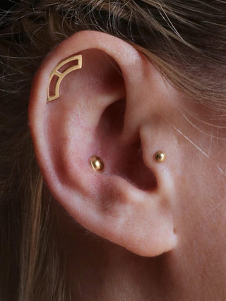 styled ear with helix conch and tragus piercing jewelry in 14k gold